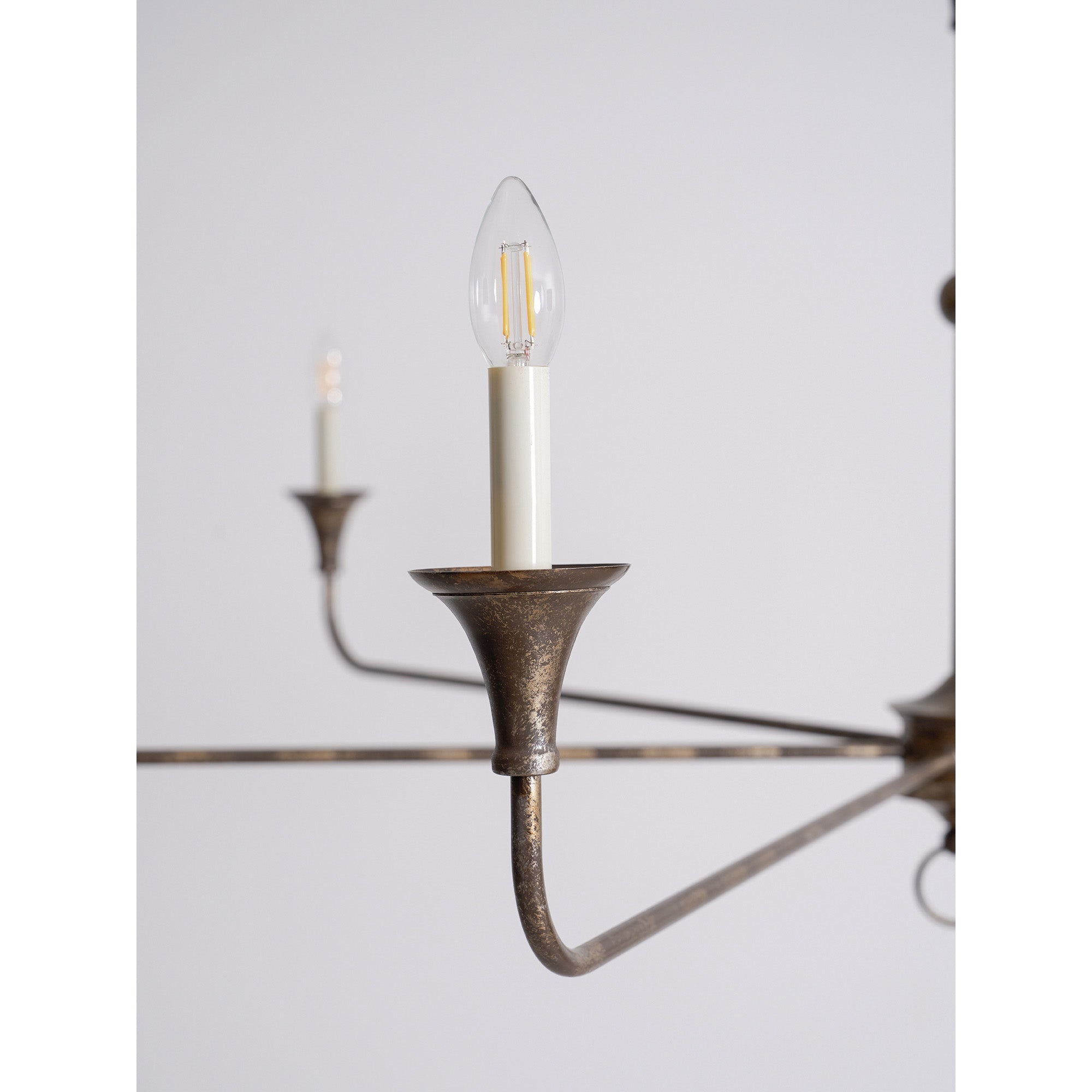 Candle chandelier finish detail on a curved brass arm