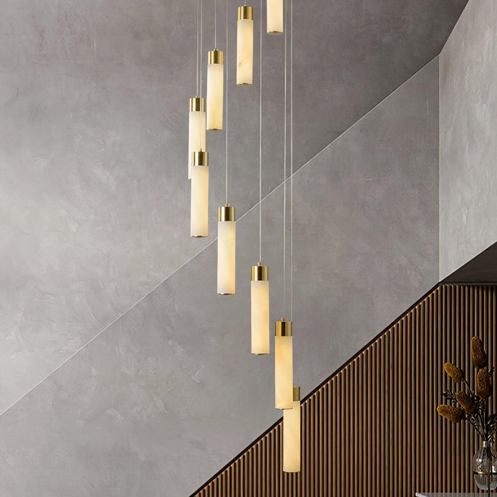 Aurelia pendants beside a concrete stair wall, the lit alabaster reading warm against cool plaster.