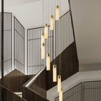 Aurelia pendants lit in the evening over a dark-timber staircase with black grille screens.