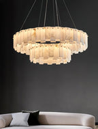 Aero round chandelier against a charcoal wall above a cream sofa, unlit so the stone reads pale grey