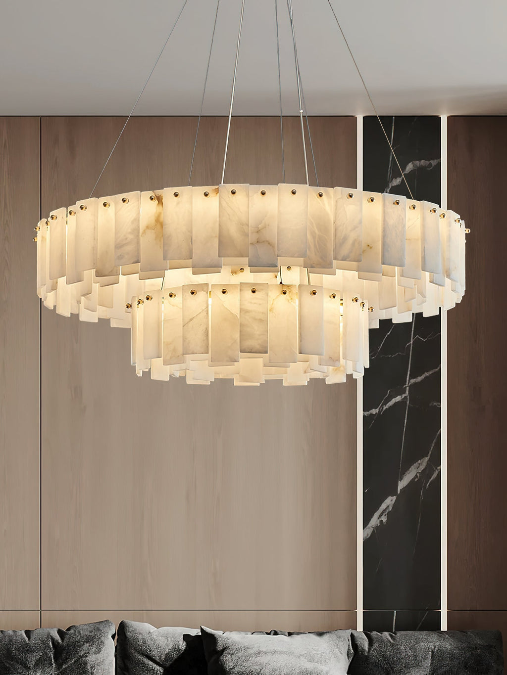 Aero round chandelier lit in front of a wood-panelled wall with a black marble inlay
