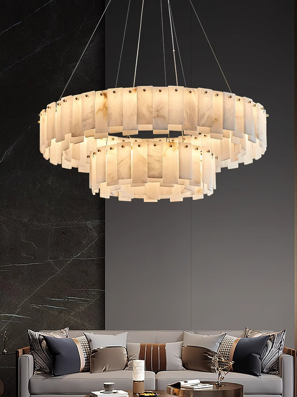 Aero round chandelier lit above a grey sofa, with a dark marble feature wall to one side
