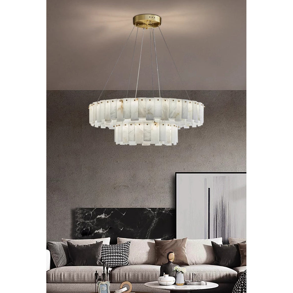Aero round chandelier above a cushioned sofa on a concrete wall, its stepped lower tier catching the light