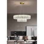 Aero round chandelier above a cushioned sofa on a concrete wall, its stepped lower tier catching the light