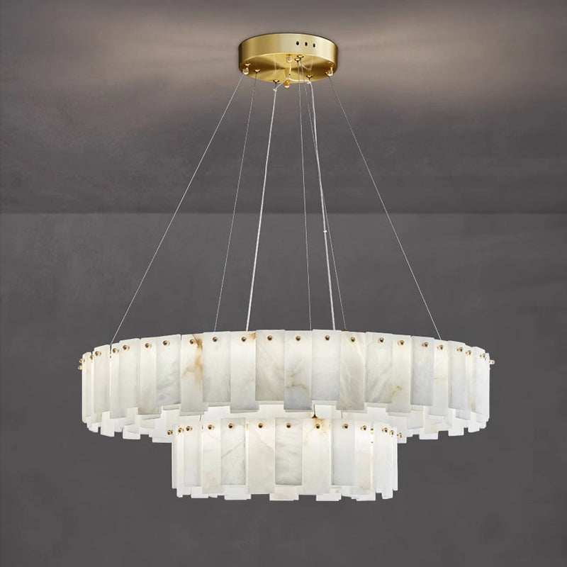 Aero round chandelier hanging against a grey concrete wall, amber veining running through the alabaster tiers