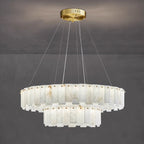 Aero round chandelier hanging against a grey concrete wall, amber veining running through the alabaster tiers