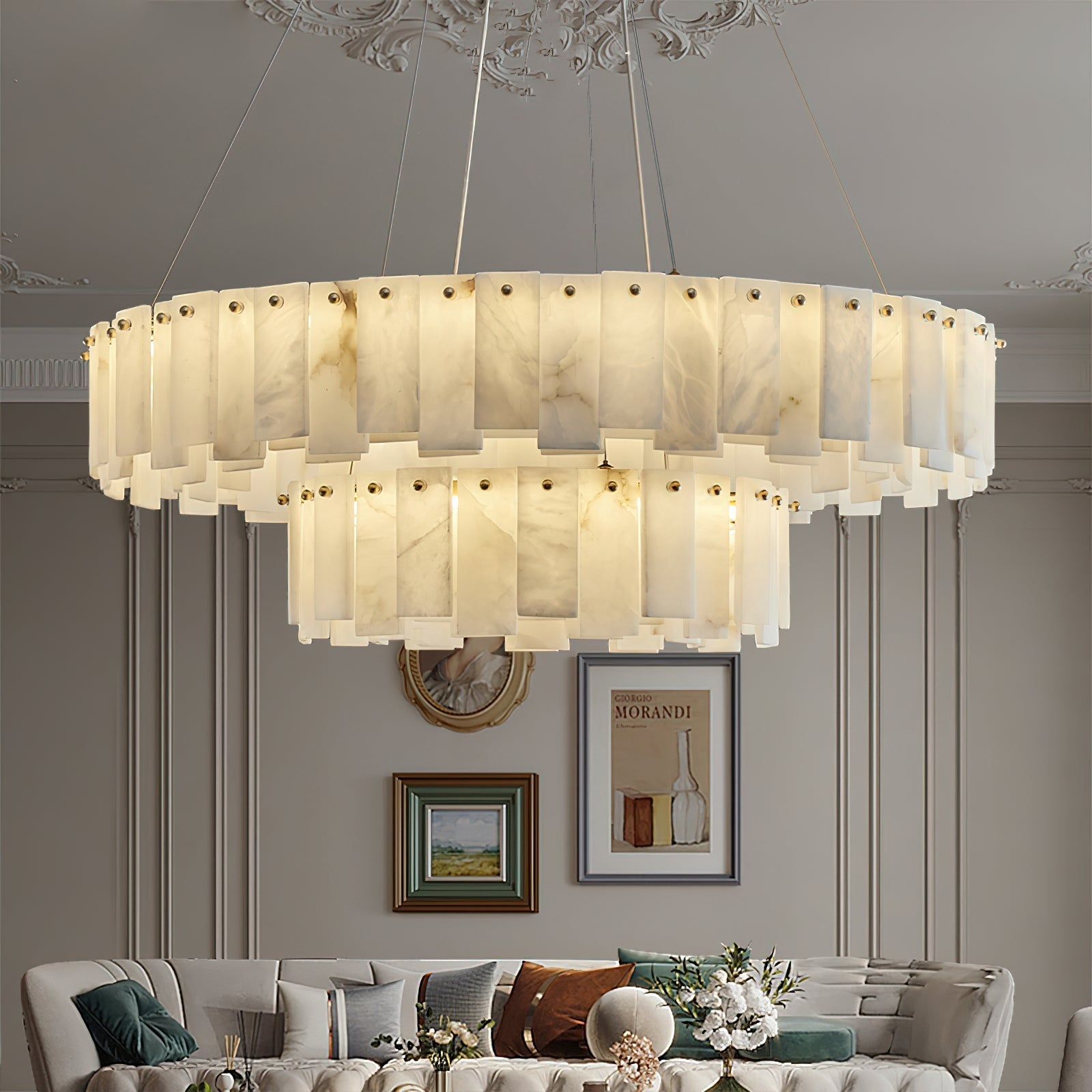 Aero round chandelier lit in a classic room beneath an ornate ceiling rose, above a tufted sofa