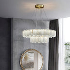 Aero round chandelier lit against a marble wall above a round gilt mirror and sheer curtains