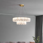 Wide view of the Aero round chandelier lit on slim cables against a plain grey wall