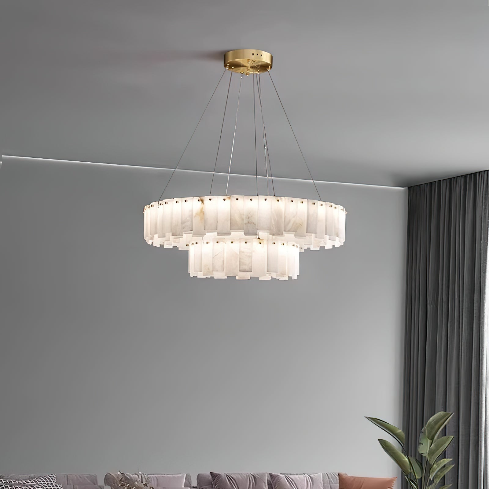 Wide view of the Aero round chandelier lit on slim cables against a plain grey wall