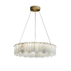 Round drum chandelier on white, stepped alabaster tiles set around a brass ring below the ceiling plate.