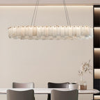 The long version lit above a dining table in a beige room with a tall shelving unit.
