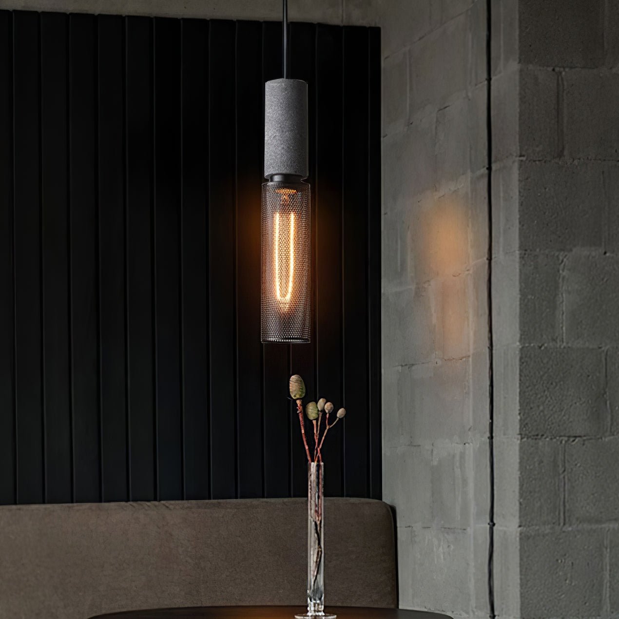 Cement mesh pendant light hanging beside a brick wall