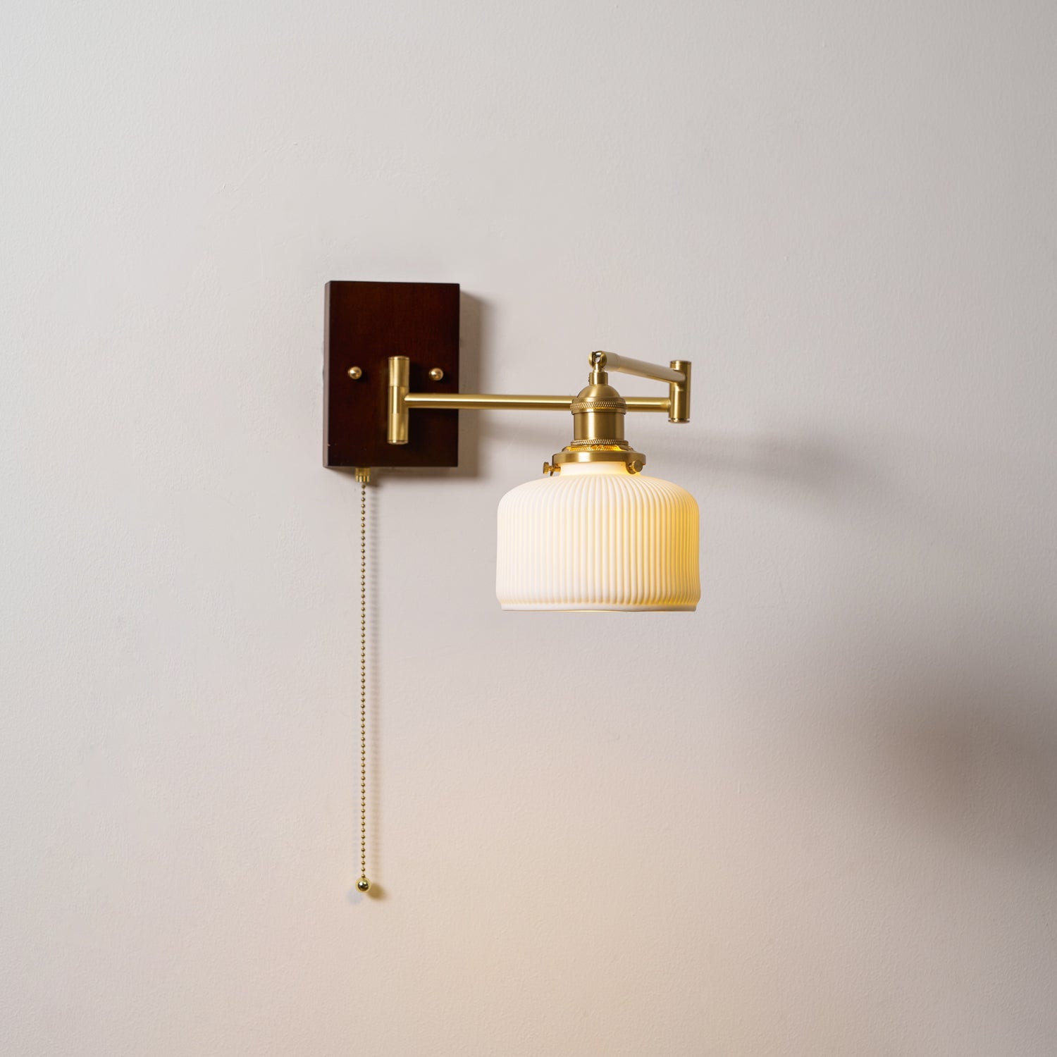 Sculptural white ceramic wall lamp on brass mount lit warmly
