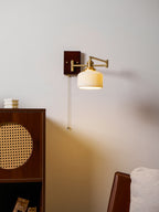 Ceramic wall lamp with pull chain and brass arm in a warm room