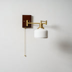White ceramic wall lamp detail with brass fittings and walnut trim