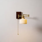 White ceramic wall lamp with pull chain mounted beside a bedside