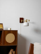 Sculptural ceramic wall lamp glowing softly with brass detail