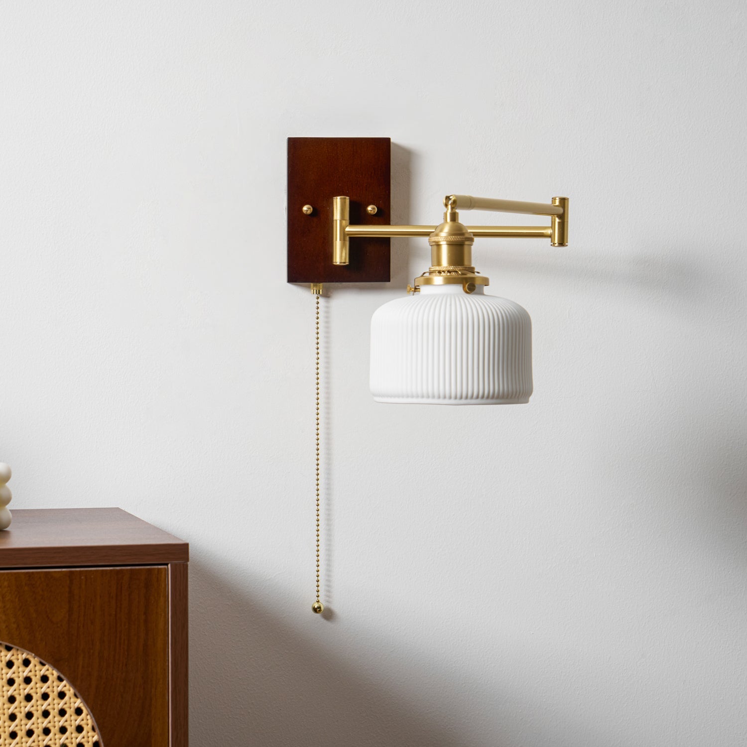 Sculptural white ceramic wall lamp on brass against a soft wall
