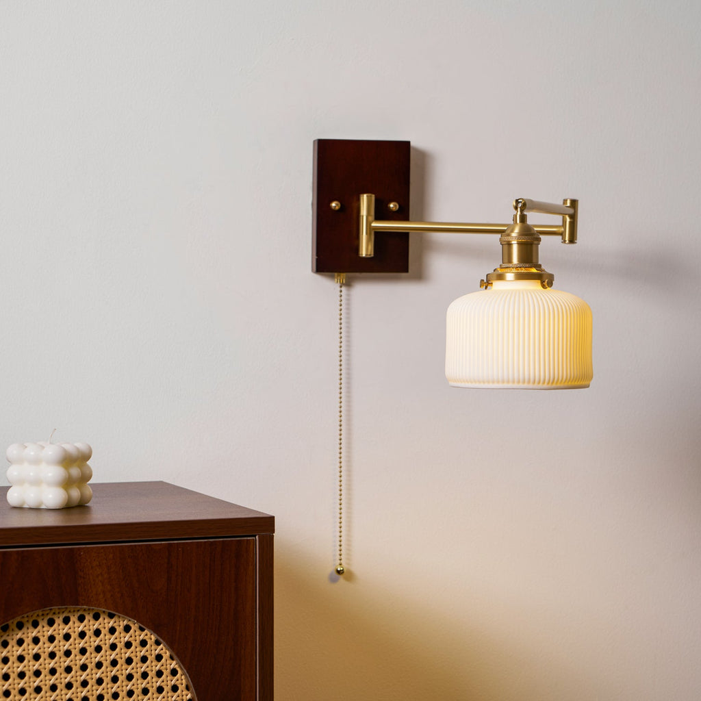 Ceramic wall lamp with pull chain shown against a neutral wall