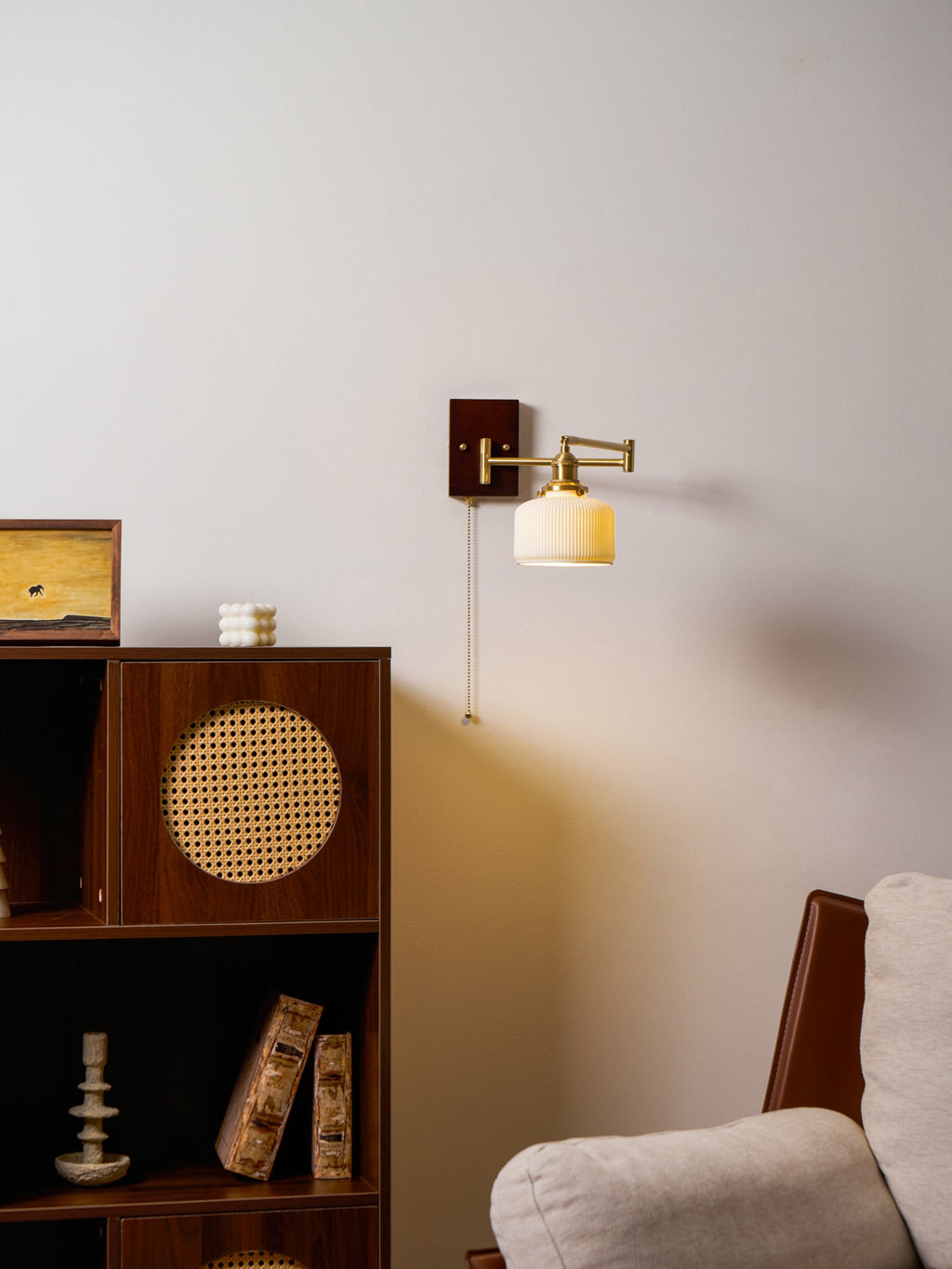 White ceramic wall lamp glowing softly with brass and walnut base