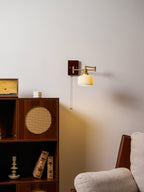 White ceramic wall lamp glowing softly with brass and walnut base