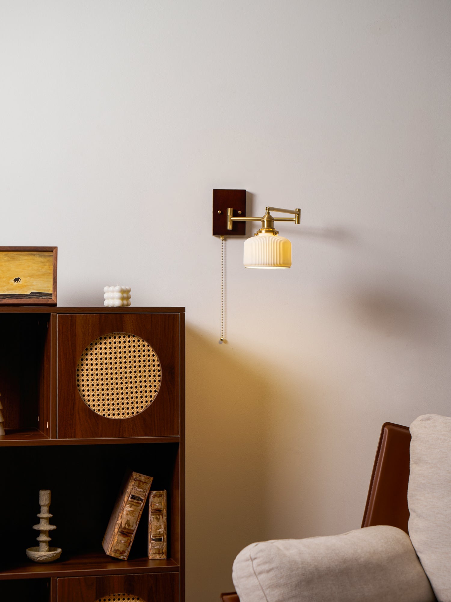 White ceramic wall lamp glowing softly with brass and walnut base