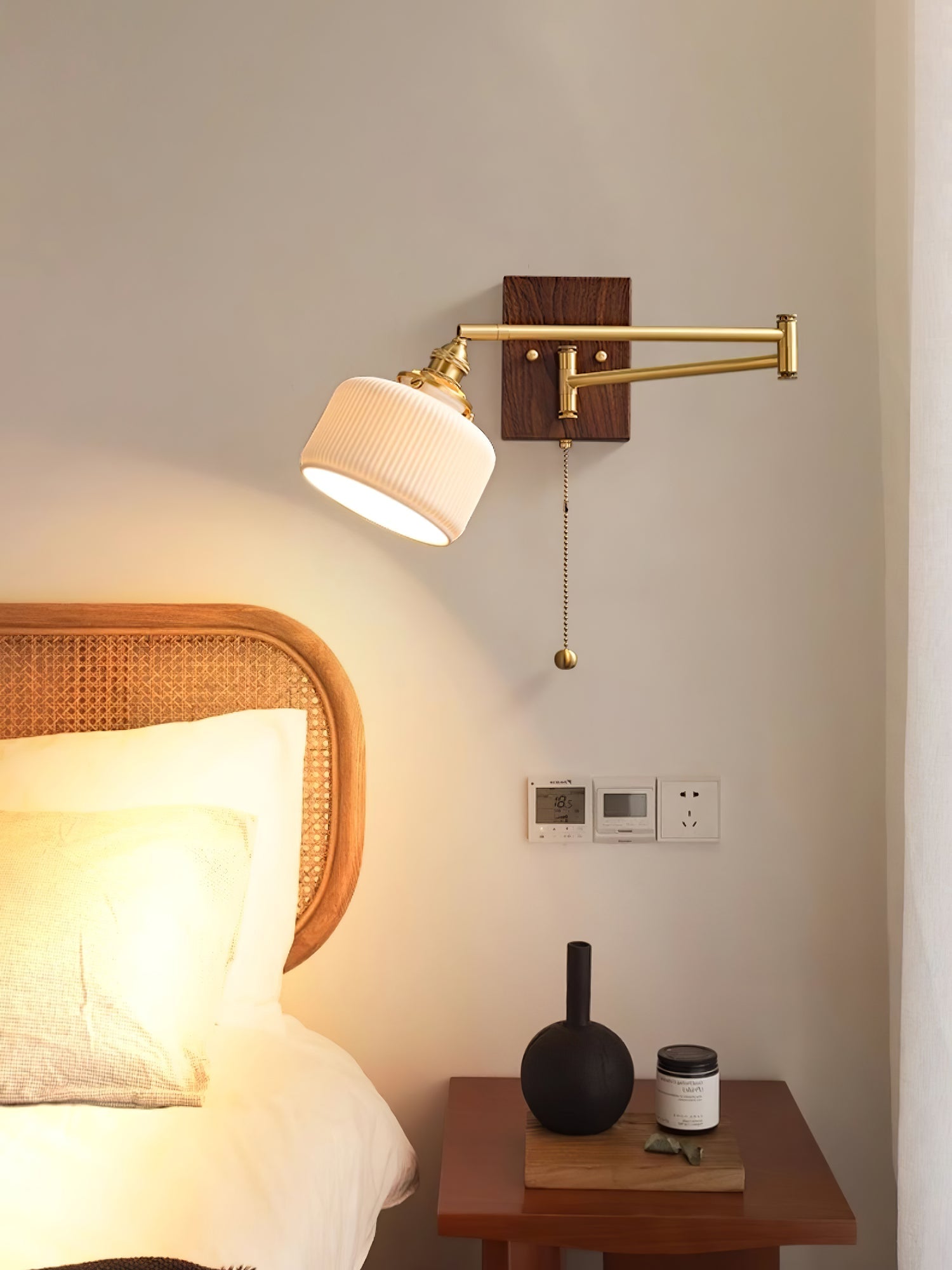 White ceramic wall lamp with brass hardware in a styled room