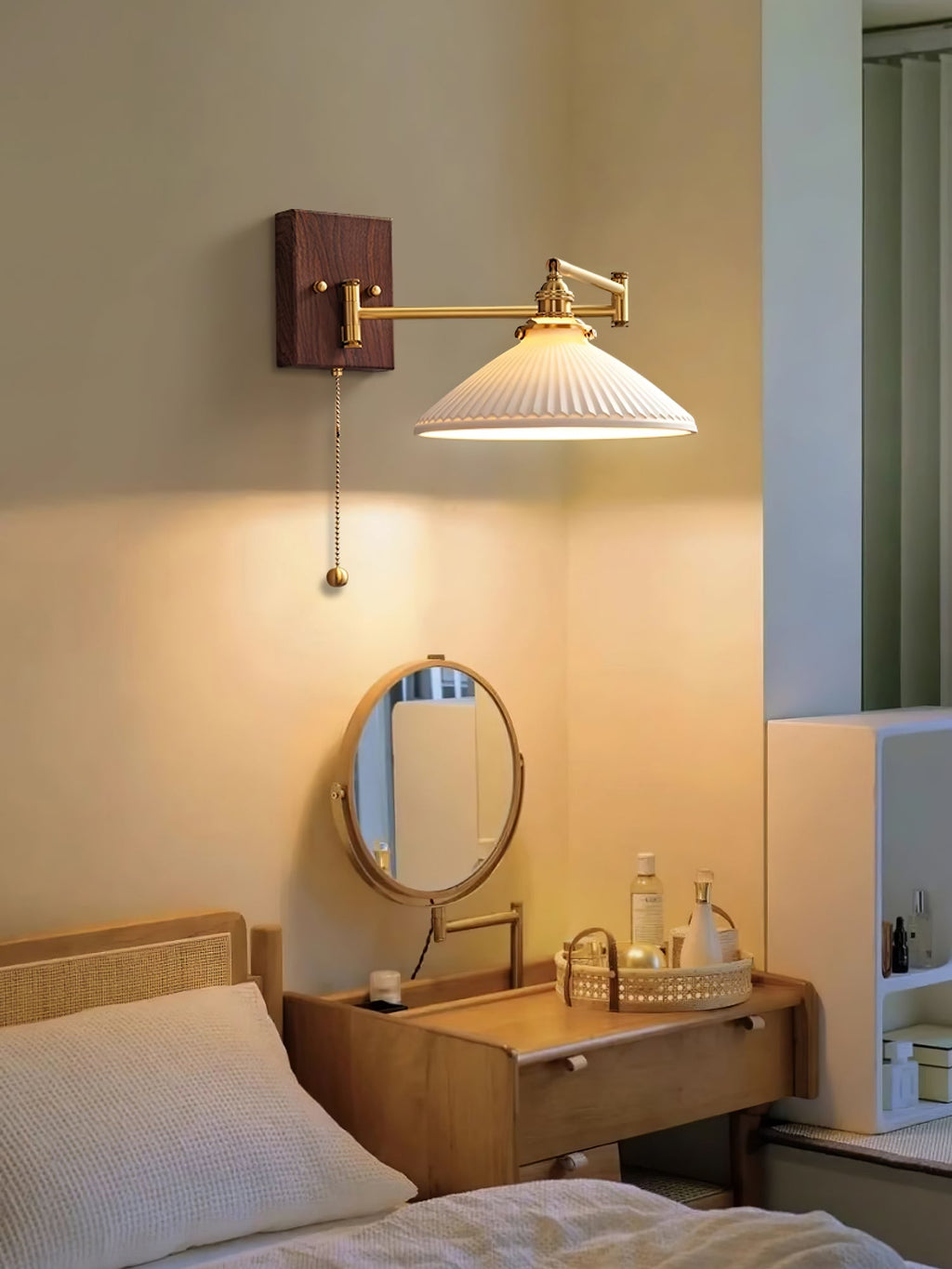 White ceramic wall lamp on walnut and brass beside a reading chair