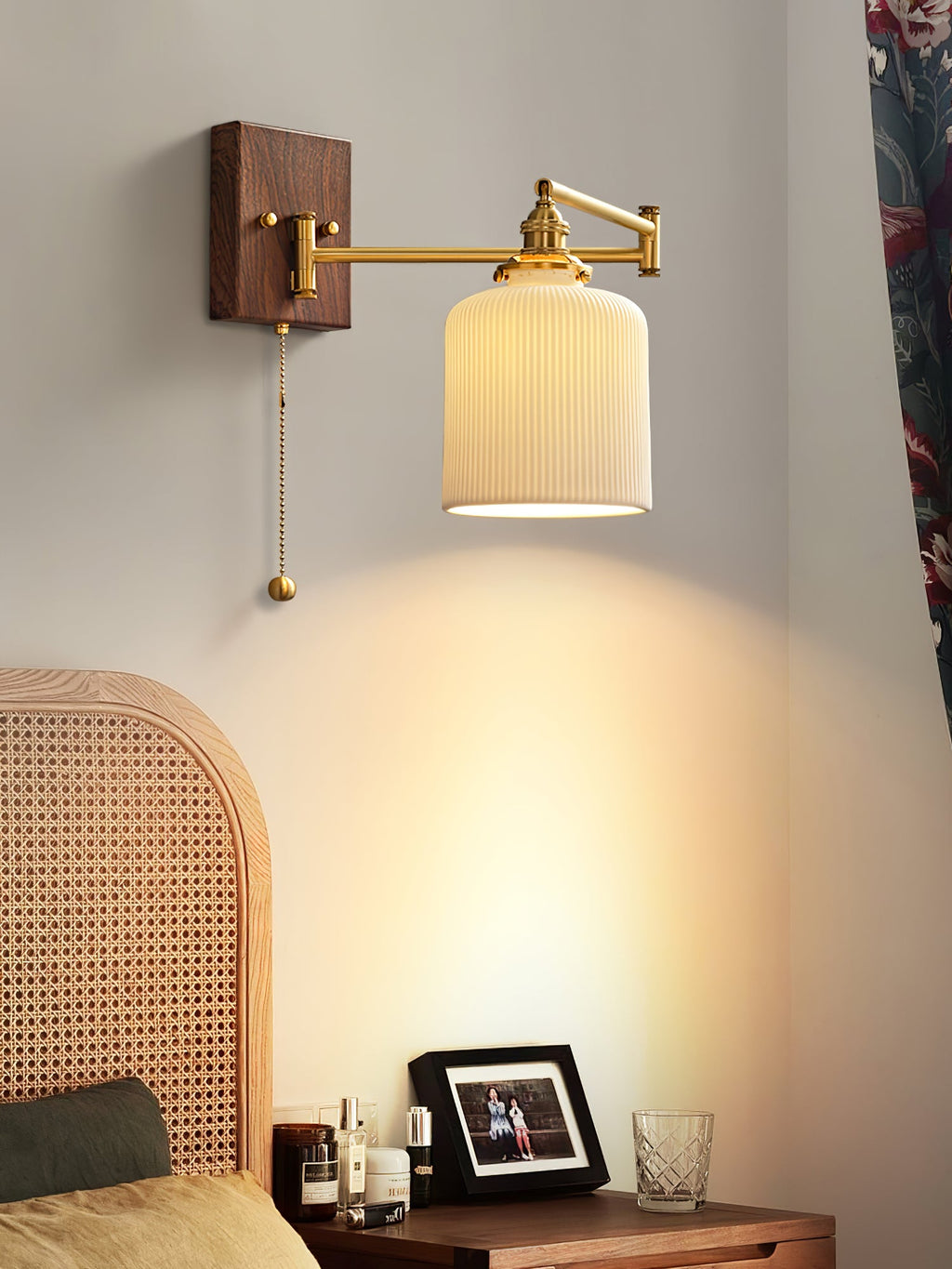 Ceramic wall lamp with pull chain and brass arm glowing warmly