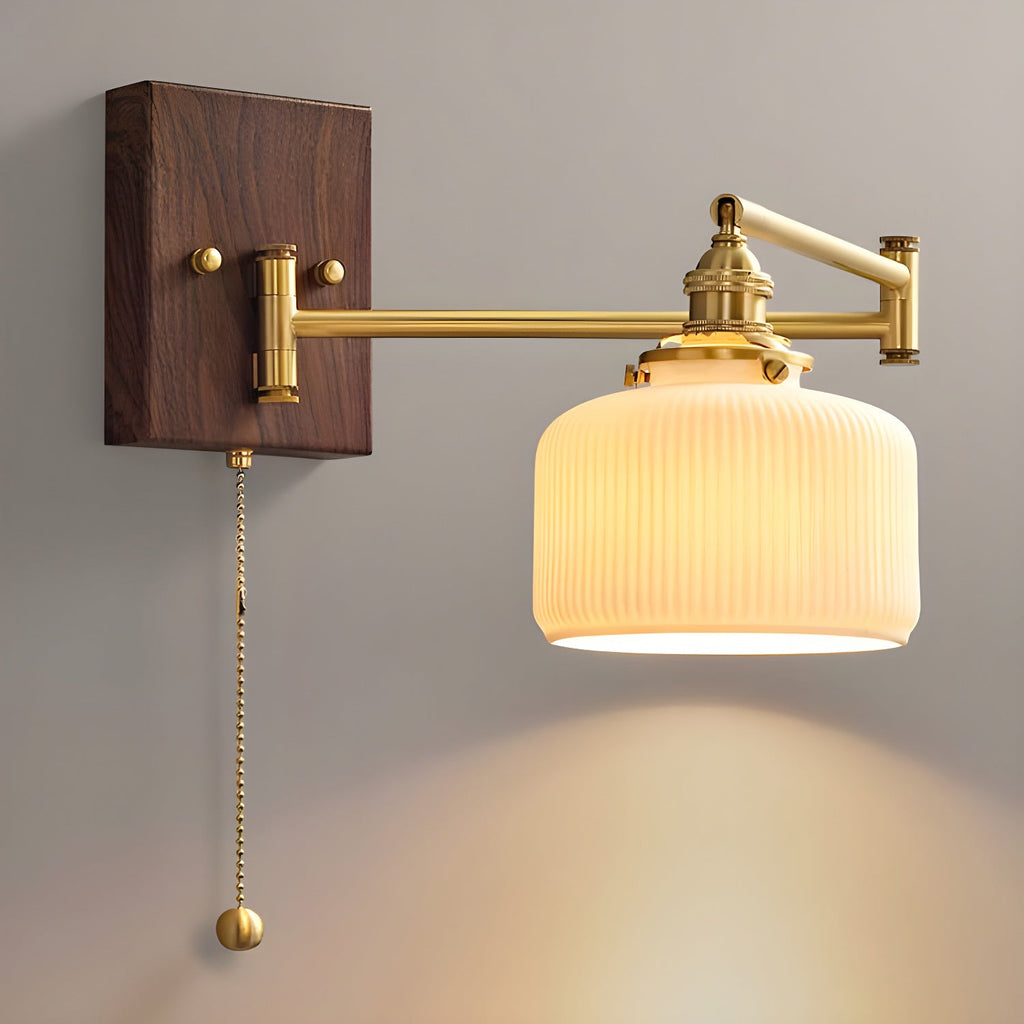 White ceramic wall lamp on brass and walnut glowing softly indoors