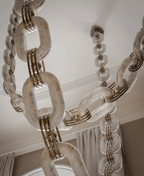 Upward crop of the stone chain, showing the veining in each link and the ceiling canopy