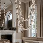 Close view of the chandelier's stone swags in front of long curtains and a marble mantel