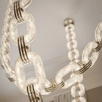 Lit chain links glowing translucent, brass collars and the slim drop cable visible above