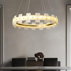 The ring lit above a dark sideboard holding a stone sculpture, in a cream-walled room.