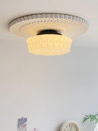 Ceiling light with black frame and white glass shades lit softly