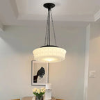 Above a dining table set with tulips, this beige fluted-glass Clérachic pendant glows beside a framed print on the wall.