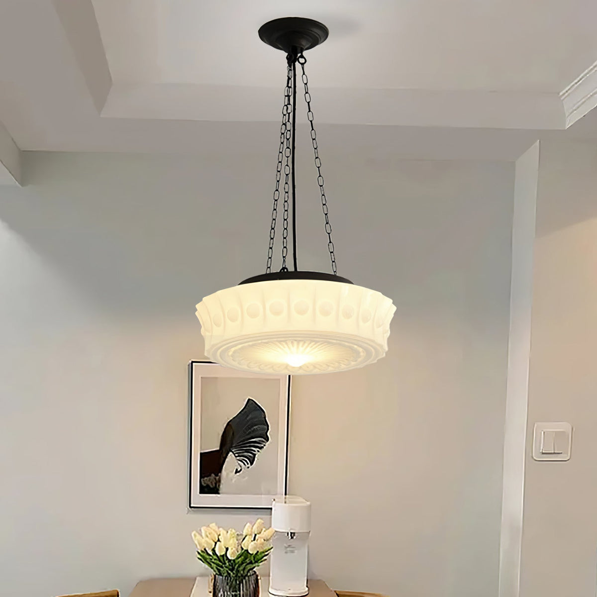 Above a dining table set with tulips, this beige fluted-glass Clérachic pendant glows beside a framed print on the wall.