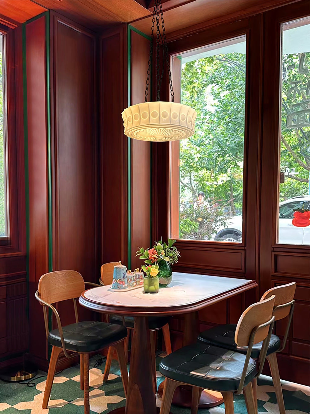 Over a small round table and chairs, this beige fluted-glass Clérachic pendant hangs in a wood-panelled bay-window nook.