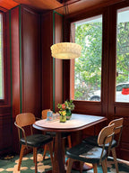 Over a small round table and chairs, this beige fluted-glass Clérachic pendant hangs in a wood-panelled bay-window nook.