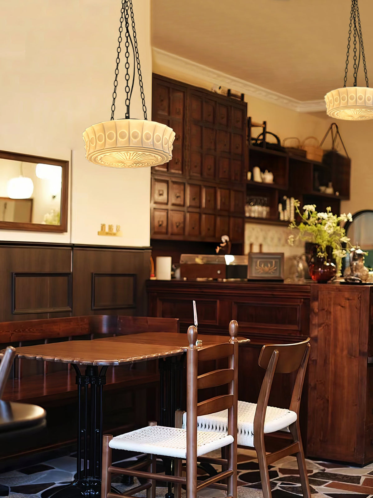 Two beige fluted-glass Clérachic pendants hang in a rustic kitchen with dark wood cabinetry and a table set for dining.