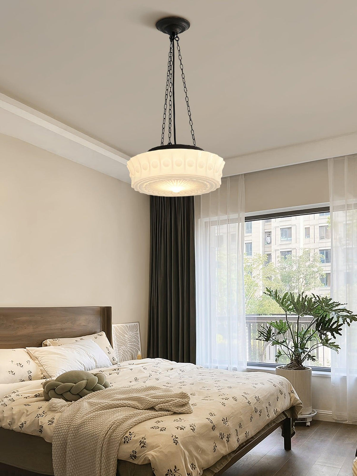 In a bedroom with a large window and a dark curtain, this beige fluted-glass Clérachic pendant glows beside a potted plant.