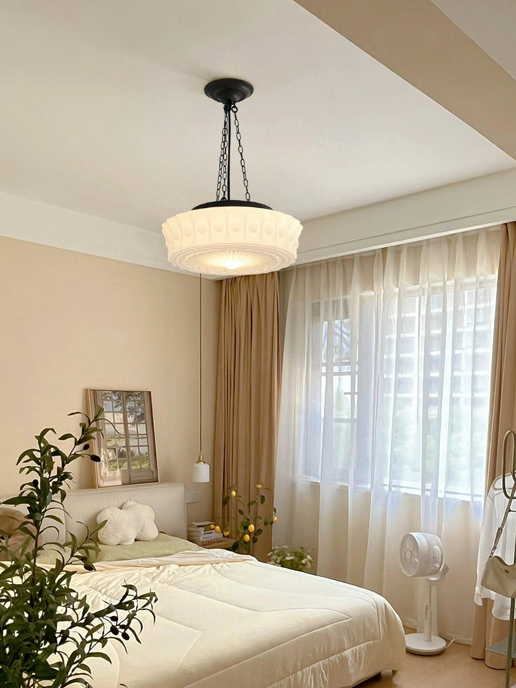 In a bedroom with sheer and gold curtains, this beige fluted-glass Clérachic pendant glows beside a floor fan.