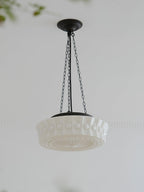 A low-angle studio view of this white fluted-glass Clérachic pendant, its ribbed edge and canopy set against a plain background.