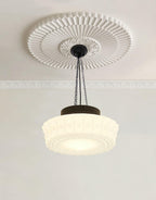 Beneath a round ribbed ceiling medallion, this beige fluted-glass Clérachic pendant's chains meet a black canopy.