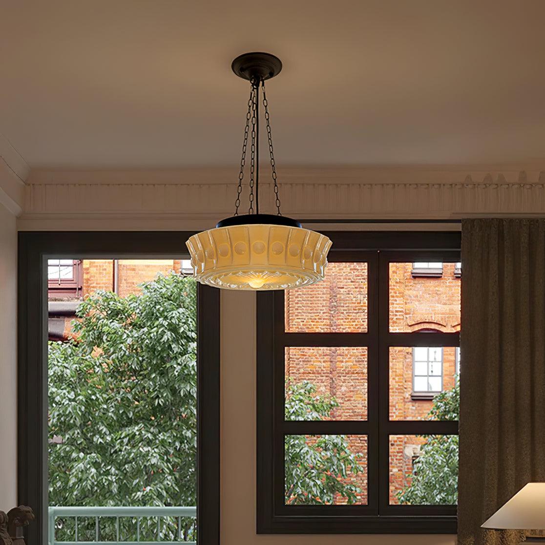 In front of a large window overlooking bare branches and a brick building, this beige fluted-glass Clérachic pendant hangs.