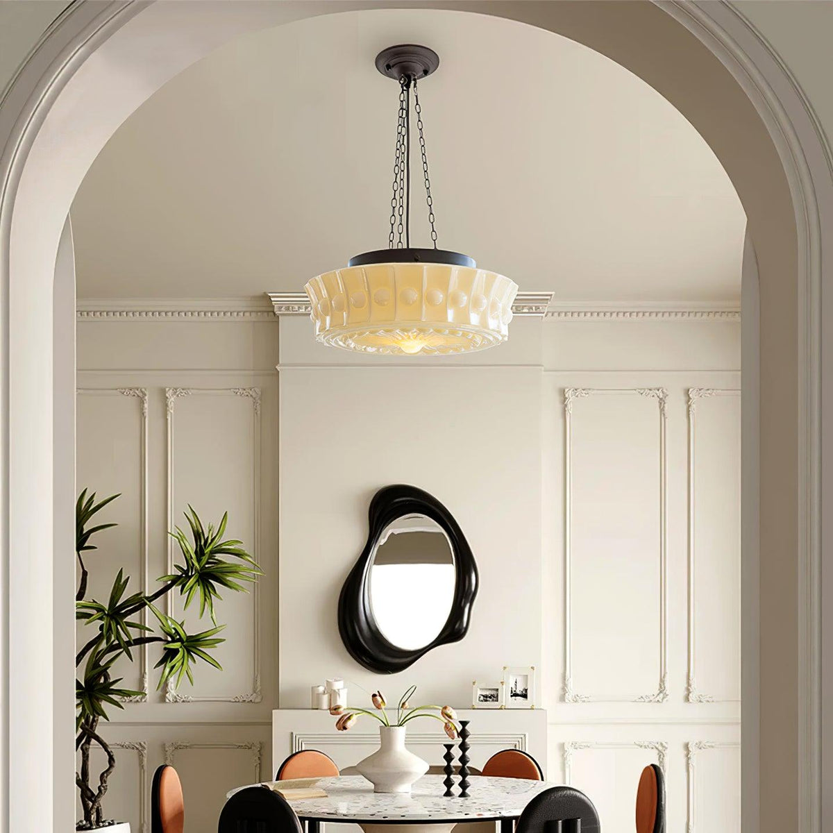 Beneath an archway near an oval mirror, this beige fluted-glass Clérachic pendant hangs above a marble-topped table.