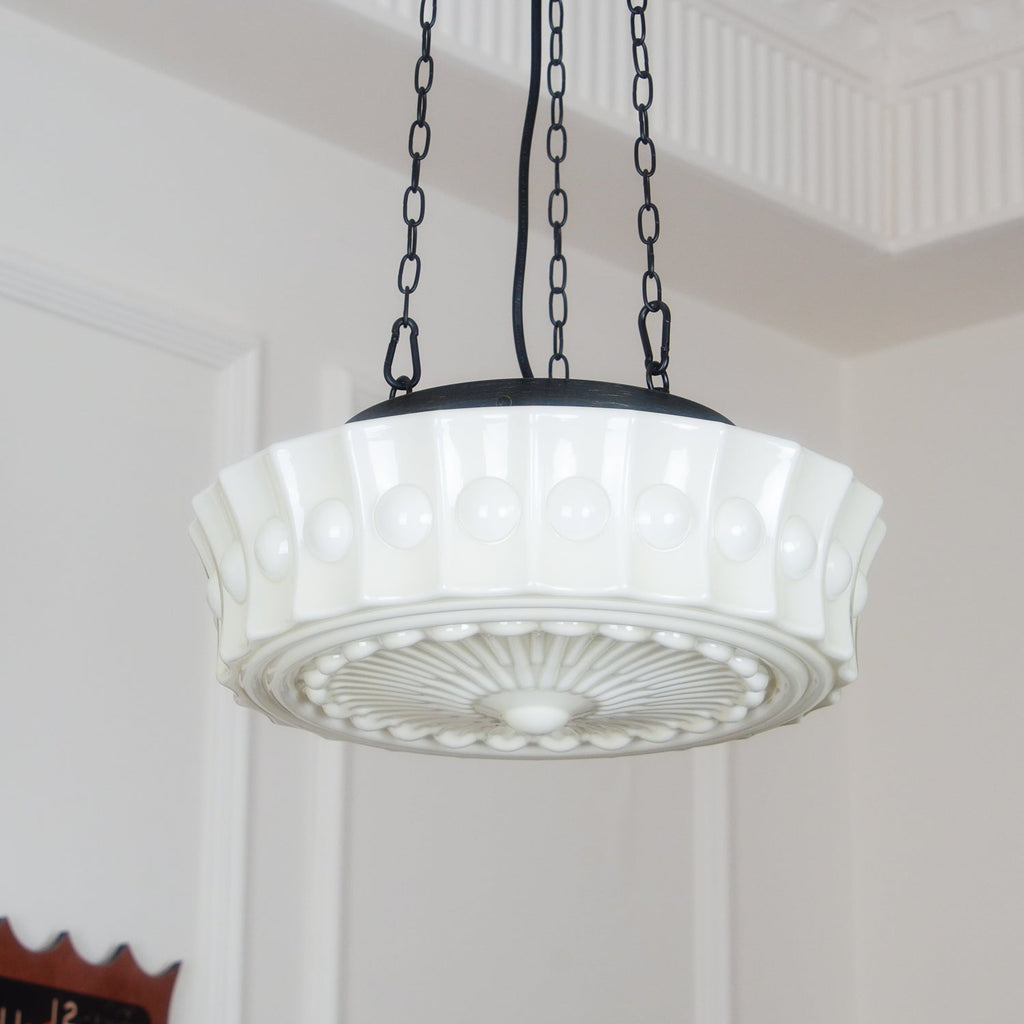 In a doorway, this white fluted-glass Clérachic pendant hangs lit, its sunburst diffuser plate clearly visible from below.
