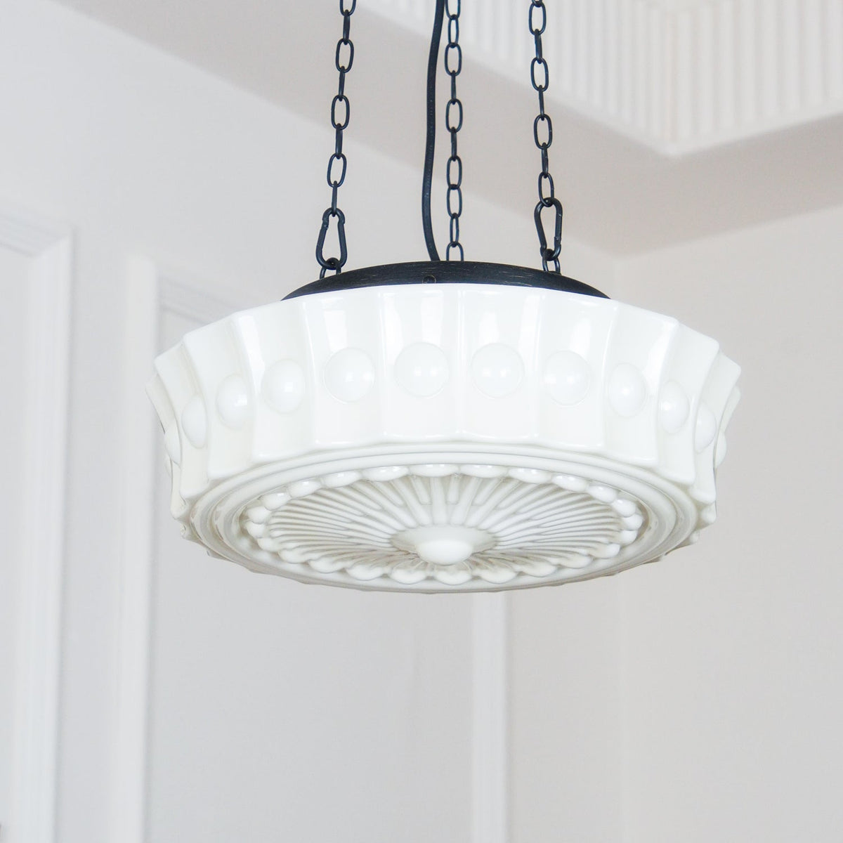 A close low-angle view of this white fluted-glass Clérachic pendant, showing the fluted ribs and sunburst diffuser in detail.