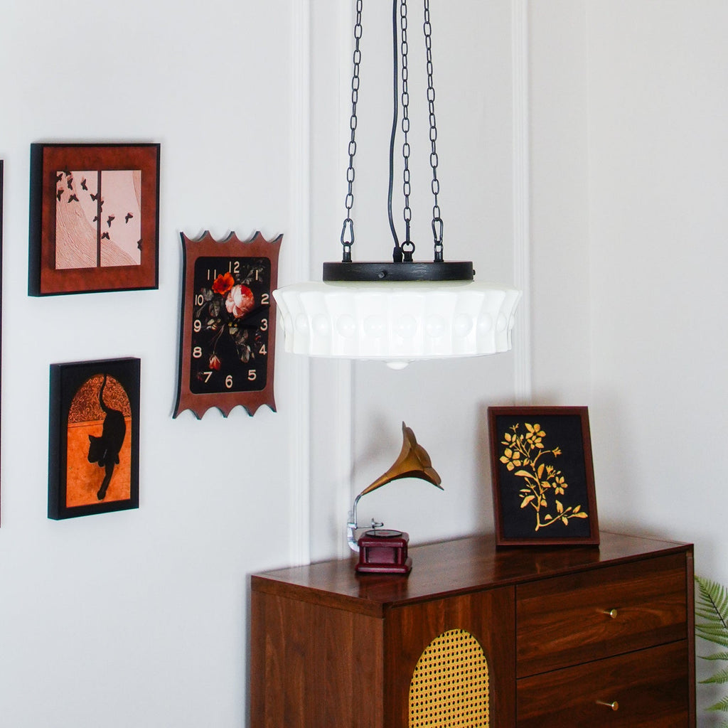 Above a wooden dresser topped with a gramophone horn, this white fluted-glass Clérachic pendant hangs near framed pictures.